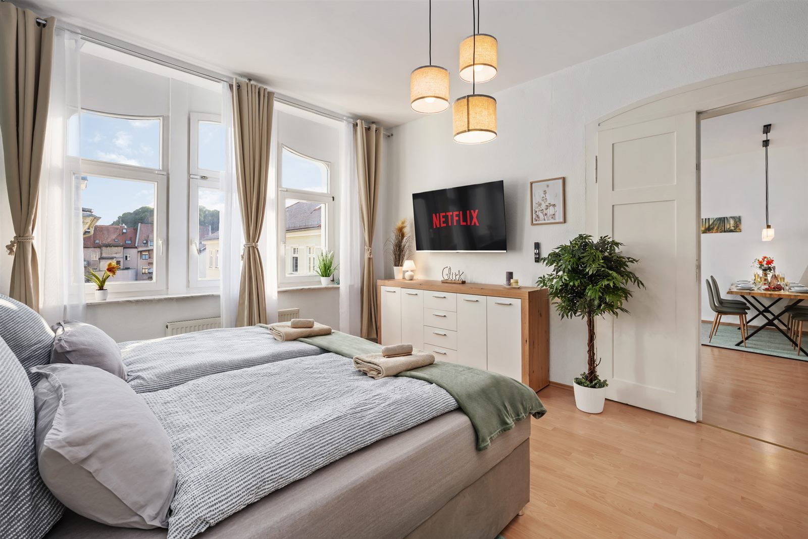 Schlafzimmer mit Smart-TV und Durchblick zum Essbereich – offen und wohnlich gestaltet