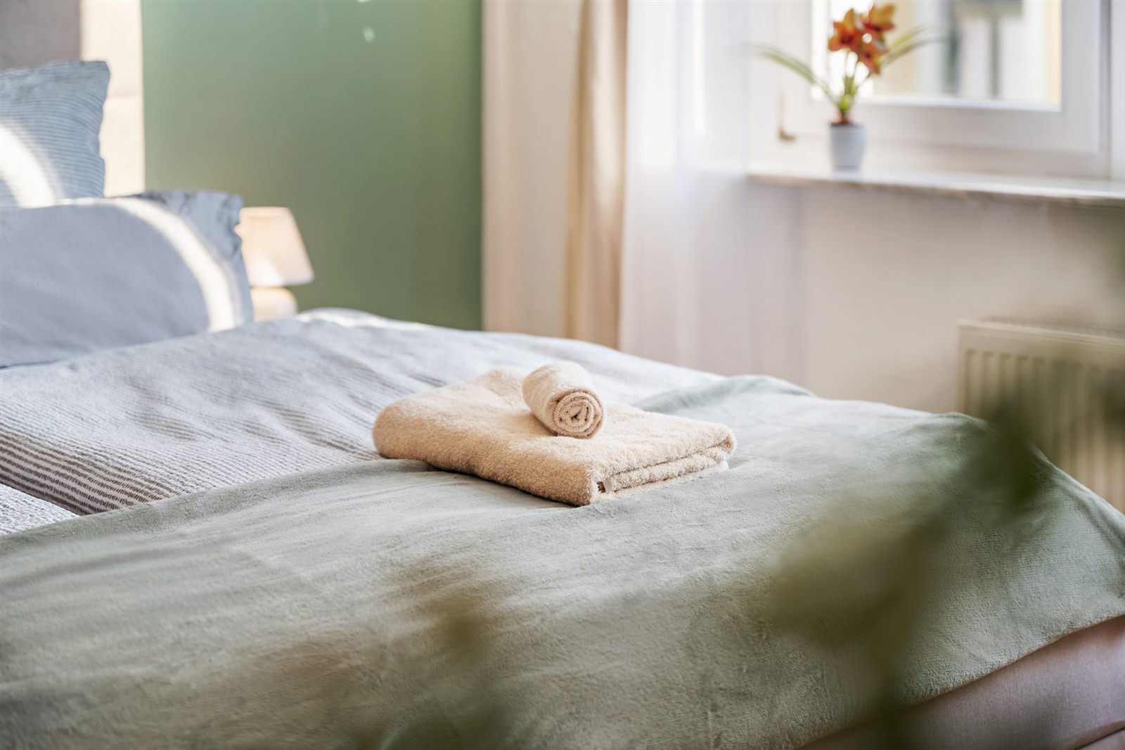 Frische Handtücher auf dem Bett und Orchidee am Fenster – liebevoll vorbereitet für Ihre Ankunft