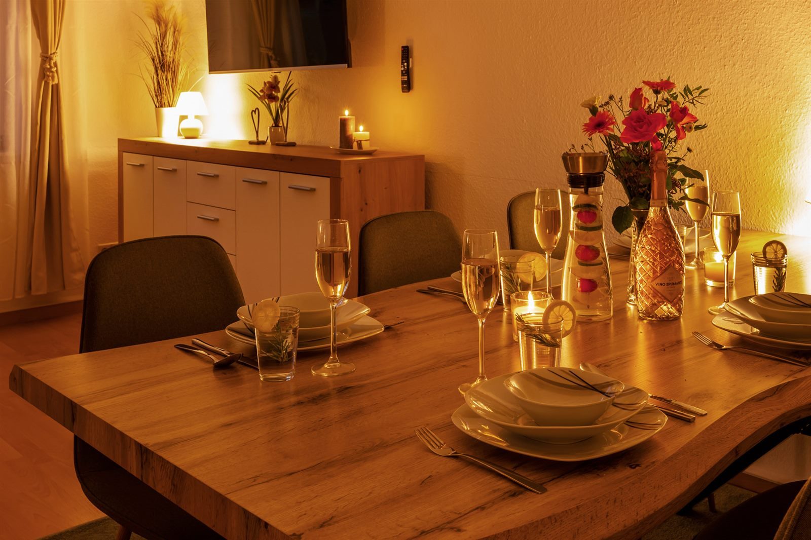 Romantisch gedeckter Esstisch bei Kerzenschein mit Sekt und Rosen – besondere Abende für Erwachsene