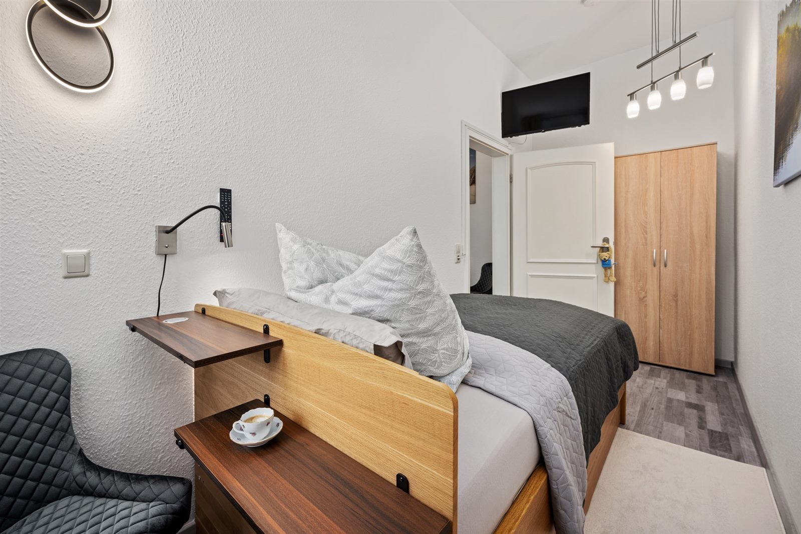 Gemütlicher Schlafbereich der SmartLuxusOase Meißen mit Boxspringbett, integriertem Ablagebrett und Designer-Leseleuchte – starten Sie entspannt mit einem Espresso ans Bett in den Tag