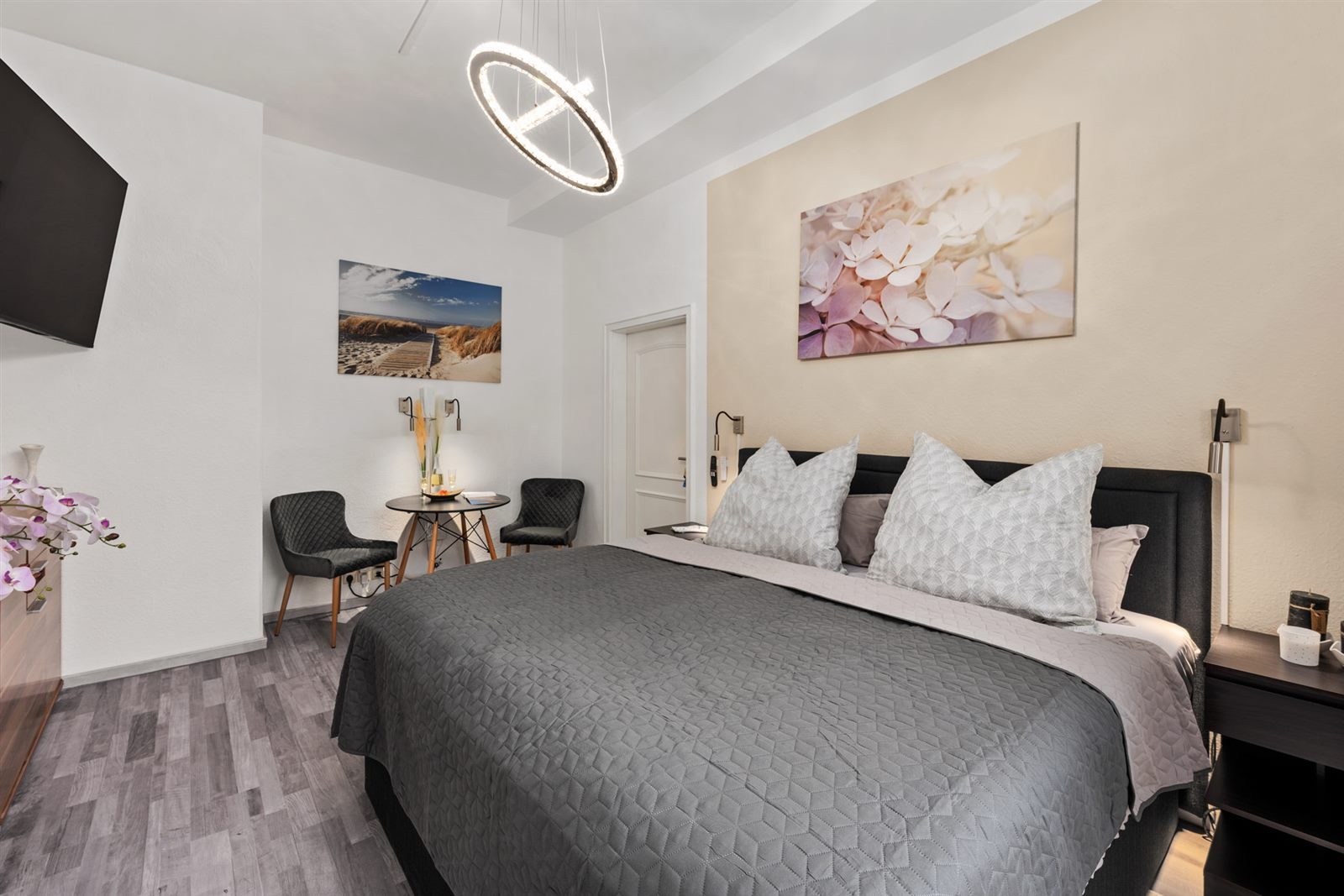 Helles Schlafzimmer der Ferienwohnung in Meißen mit edlem Boxspringbett, Designer-Ringleuchter und kleiner Sitzecke – ankommen und sofort wohlfühlen