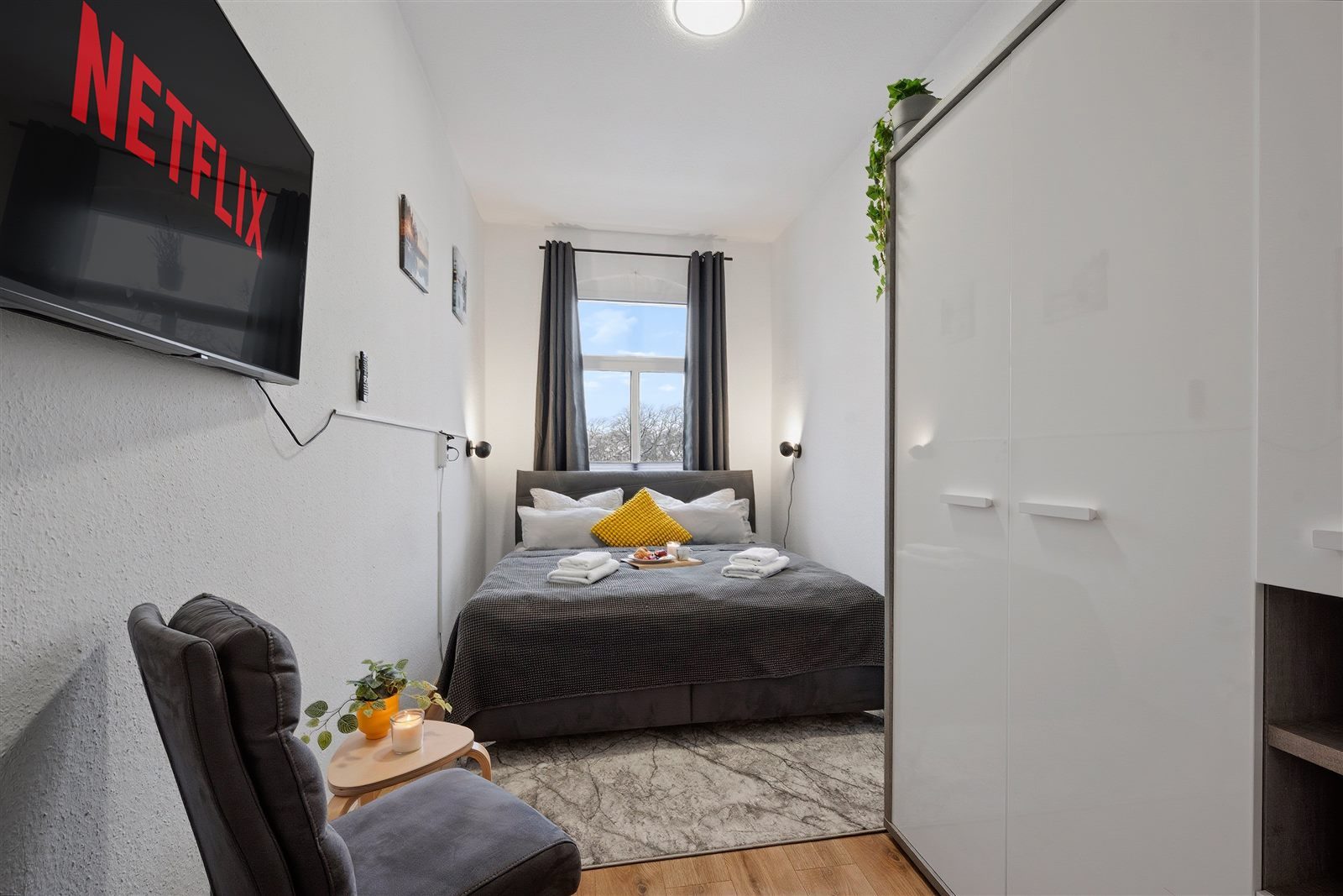Schlafzimmer mit Smart-TV, Sessel und großem Kleiderschrank – Netflix-Abend und genug Stauraum für längere Aufenthalte