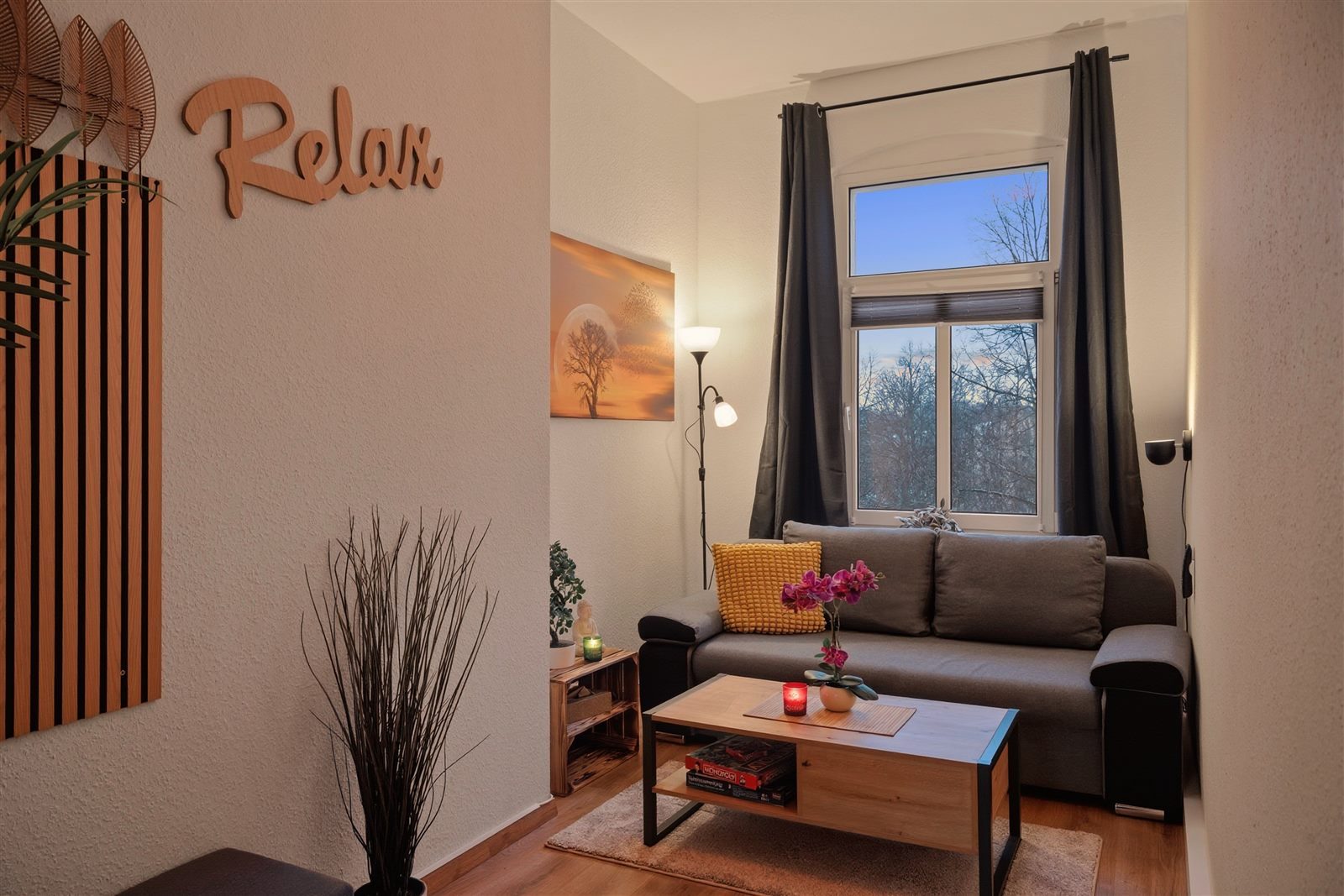 Gemütliches Wohnzimmer mit Relax-Schriftzug im Abendlicht – ankommen und loslassen
