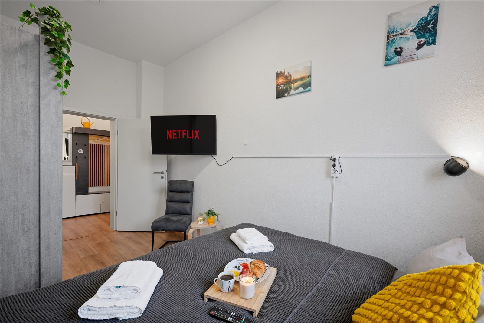 Schlafzimmer mit Smart-TV und Durchblick zur Küche – wohnlich, offen und mit Frühstück ans Bett